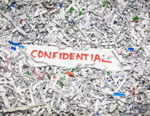 confidential word set against shredded paper