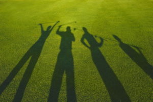 silhouette of four golfers on grass