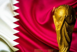 world cup trophy with qatar flag in the background