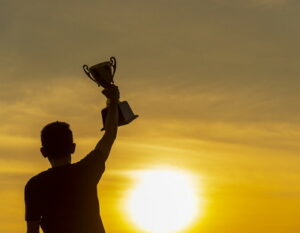 silhouette of man holding up trophy